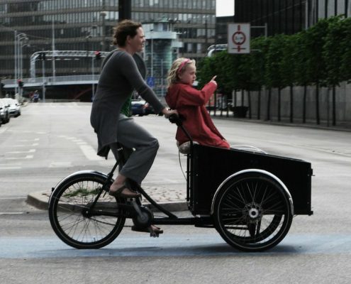 A photo of a mother cargo biking with her daughter on the bike | Copenhagen Private Biking Tour | 3 Hours | Amitylux Tours | Guided Tours | VIP & Luxury Experiences