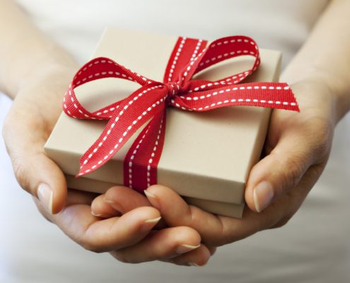 A photo of a person holding a wrapped gift with their two hands | Amitylux Gift Card | Amitylux Tours | Scandinavian Guided Tours | VIP & Luxury Experiences in the Nordics