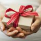 A photo of a person holding a wrapped gift with their two hands | Amitylux Gift Card | Amitylux Tours | Scandinavian Guided Tours | VIP & Luxury Experiences in the Nordics