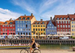 A photo of a woman biking in Nyhavn, Copenhagen during a sunny day | Copenhagen Private Walking Tour | 6 Hours| Amitylux Tours | Scandinavian Guided Tours | VIP & Luxury Experiences in the Nordics