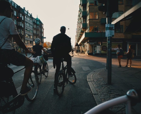 A photo of biker standing in a traffic light waiting to rde forward | Cycling in Copenhagen | The Best Ways to Be Sustainable in Denmark | Amitylux Tours | Guided City Tours | VIP & Luxury Experiences