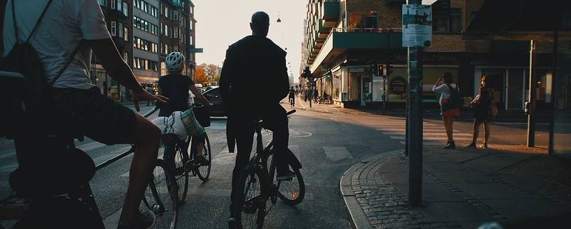A photo of biker standing in a traffic light waiting to rde forward | Cycling in Copenhagen | The Best Ways to Be Sustainable in Denmark | Amitylux Tours | Scandinavian Guided Tours | VIP & Luxury Experiences in the Nordics