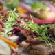 A photo of an open face sandwich with meat and green leaves and berries | The Best 5 Traditional Dishes in Denmark | Amitylux Tours | Scandinavian Guided Tours | VIP & Luxury Experiences in the Nordics
