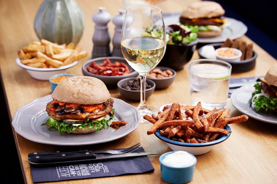 A photo of burgers, potatoes, and salad served in a table at Halifax Burgers | The Best Burgers in Copenhagen: Our Top 6 Favorite Spots | Amitylux Tours | Scandinavian Guided Tours | VIP & Luxury Experiences in the Nordics