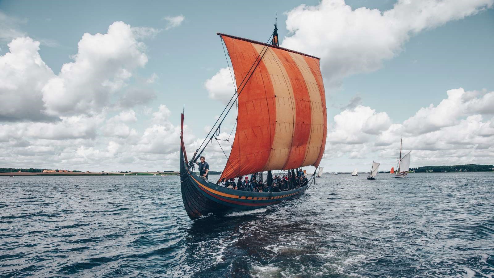 a photo of an old recreated Viking ship sailing in the sea | The Best Viking Sites in Denmark | Amitylux Tours | Scandinavian Guided Tours | VIP & Luxury Experiences in the Nordics