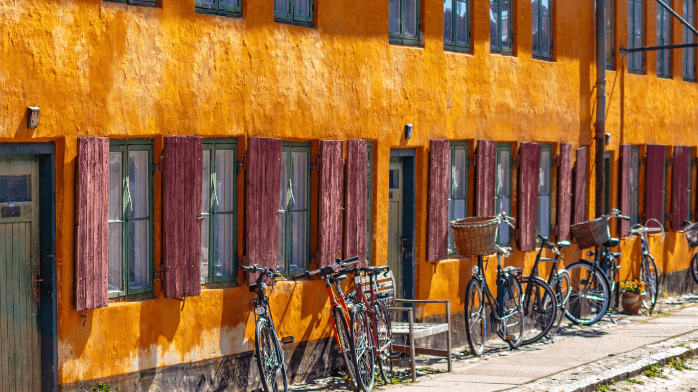 Bikes parked daytme outside of an orange painted building in Copenhagen | Amitylux Tours | Scandinavian Guided Tours | VIP & Luxury Experiences in the Nordics